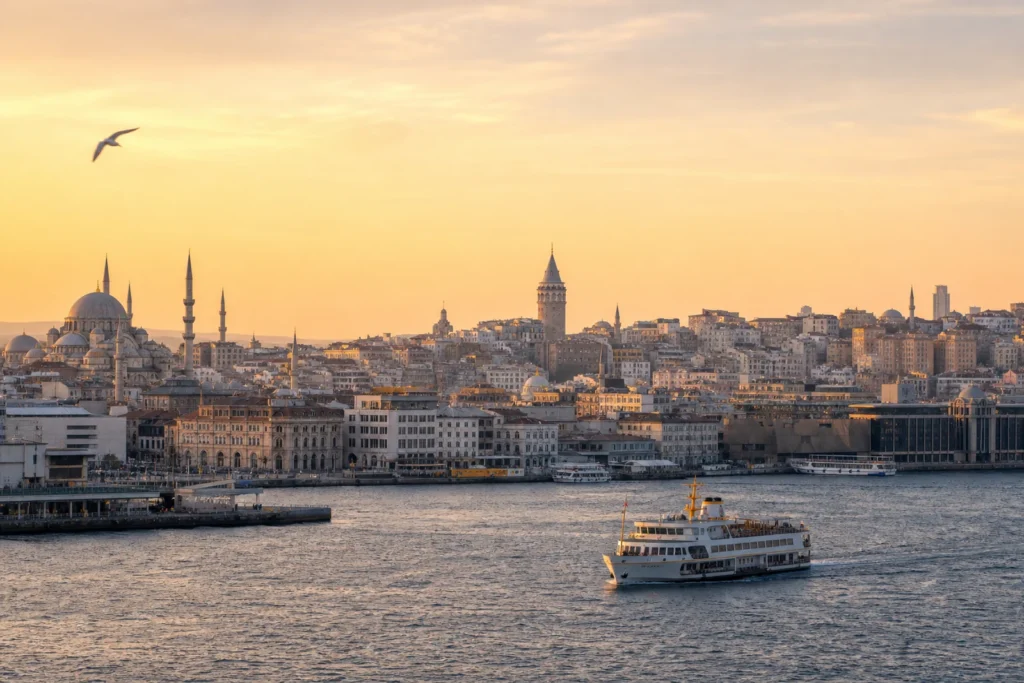Istanbul skyline across the Bosphorus with Galata Tower, historic mosques and a city ferry at sunrise